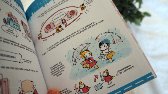 Ein Comic aus Verliebt in Japan: Zwei Freundinnen laufen mit Schirmen durch den Regen.