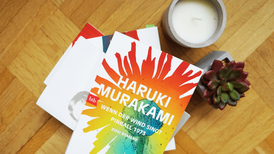 Ein Buchstapel mit Haruki Murakami-Romanen. Oben auf liegt der Doppelband Wenn der Wind singt & Pinball 1973.